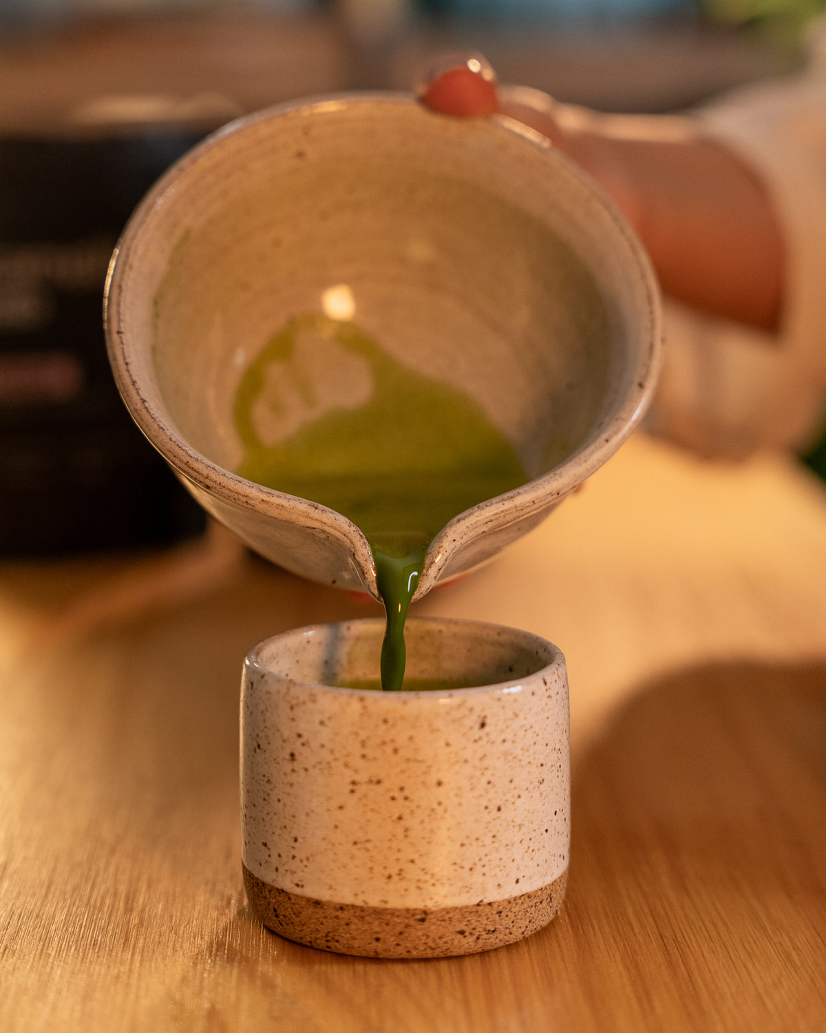 Preparo do matcha Lotus: matcha batido sendo despejado da tigela de cerâmica para a xícara